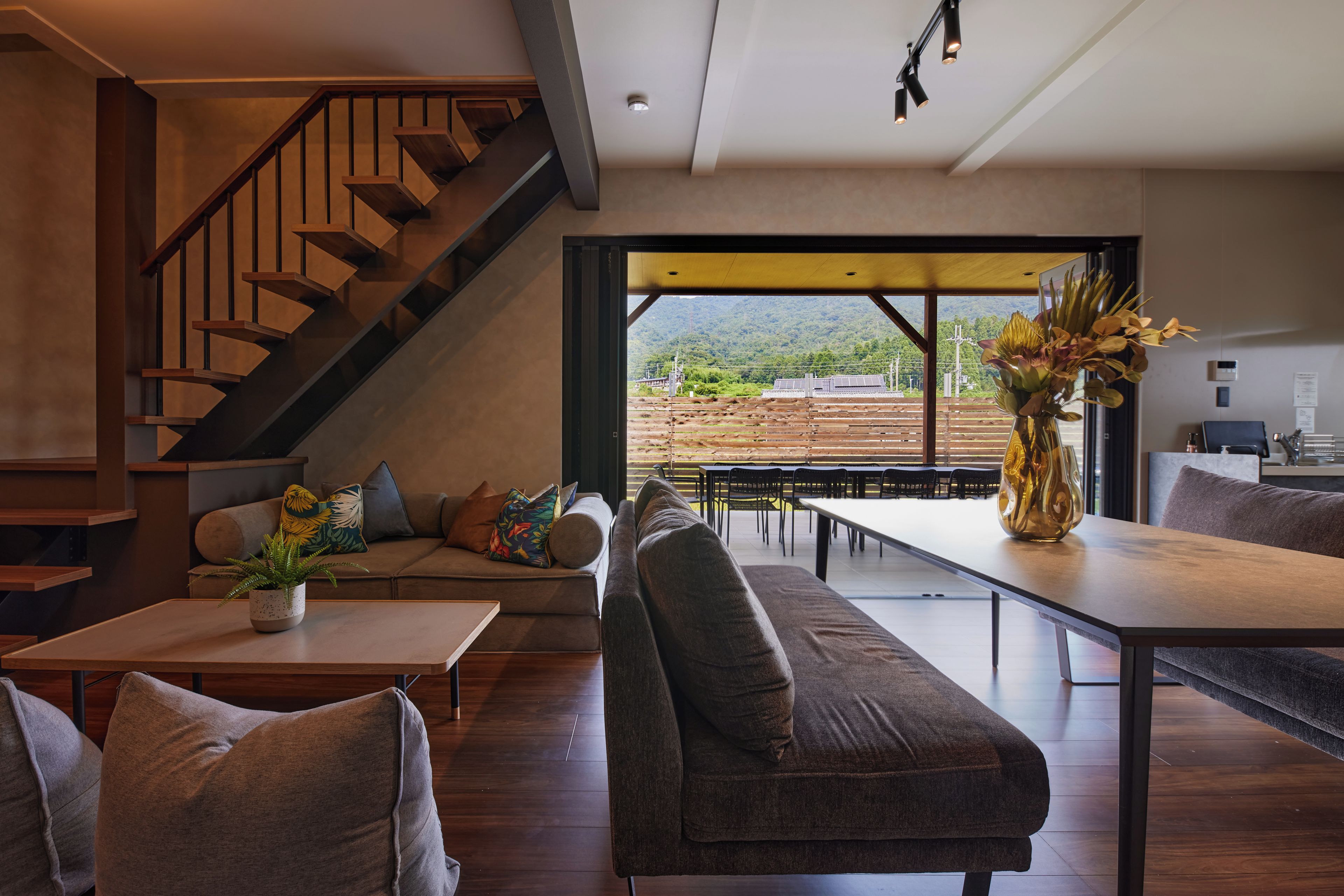 Un intérieur moderne avec un escalier, un coin salon et une vue sur un paysage montagneux.