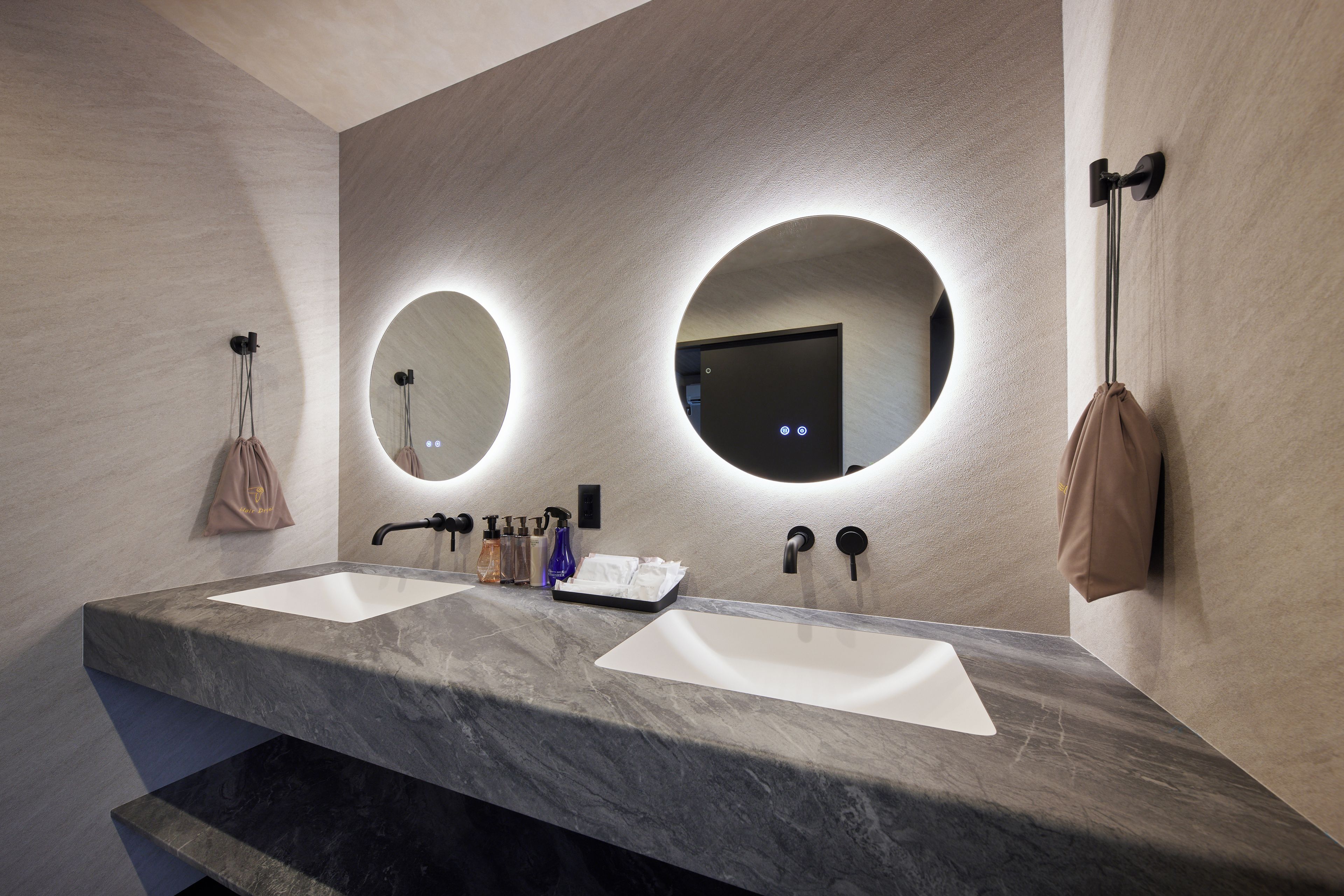 Un baño moderno con dos lavamanos, un perchero para toallas y un espejo.