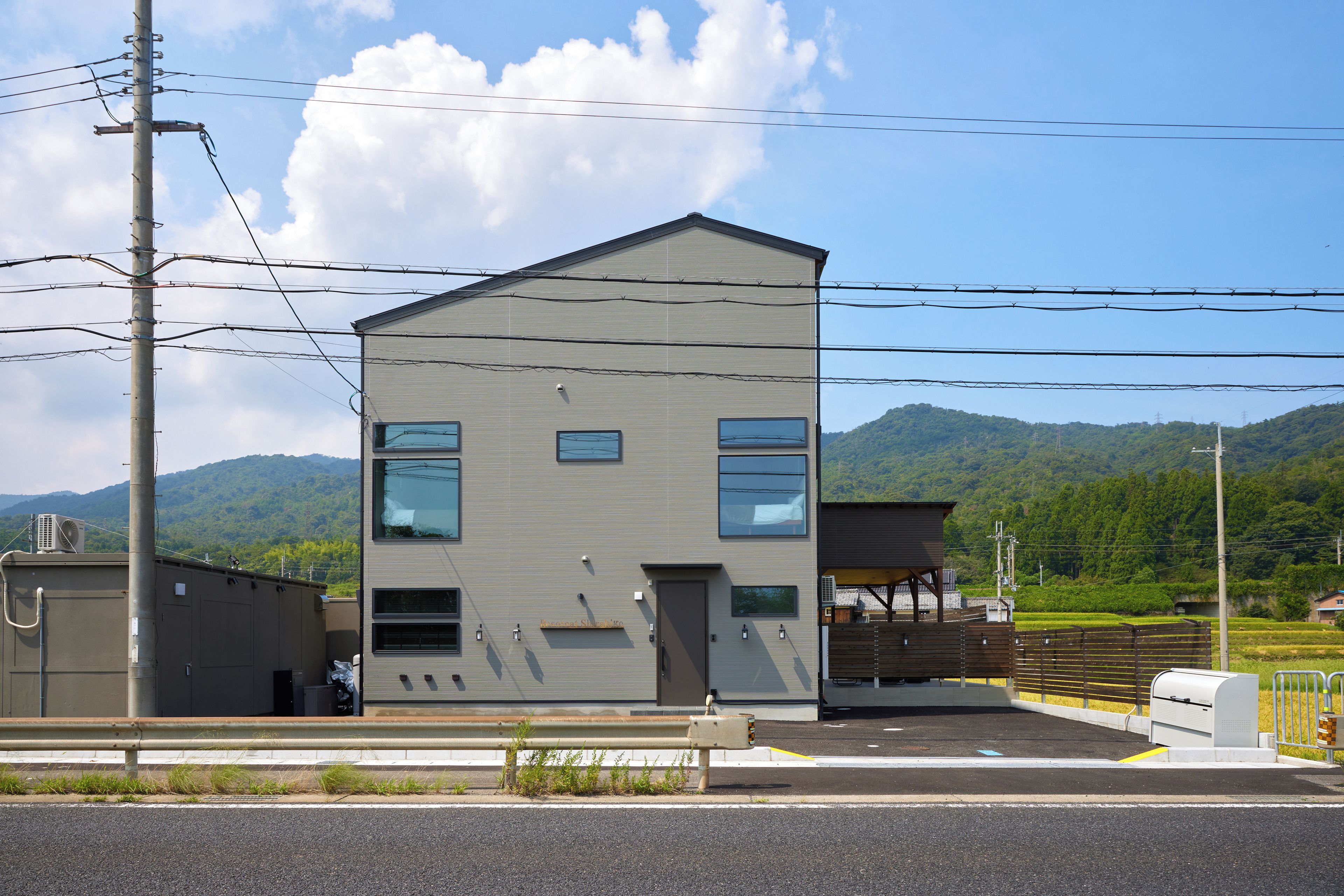 A two-story building with a flat roof, a garage, and a fenced parking area.