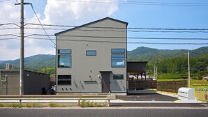 A two-story building with a flat roof, a garage, and a fenced parking area.