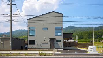 A two-story building with a flat roof, a garage, and a fenced parking area.