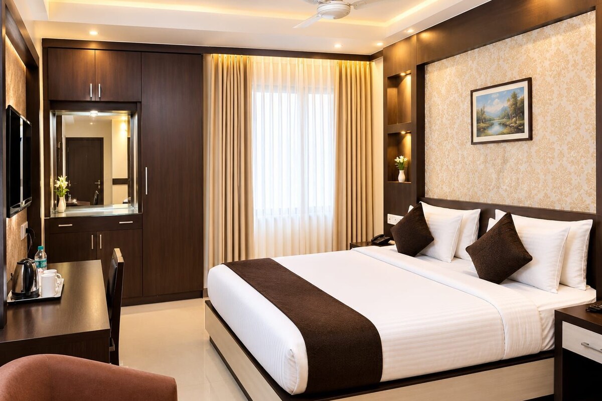Una habitación de hotel con una cama grande, un escritorio con teléfono, un espejo y un cuadro en la pared.