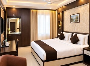 Una habitación de hotel con una cama grande, un escritorio con teléfono, un espejo y un cuadro en la pared.