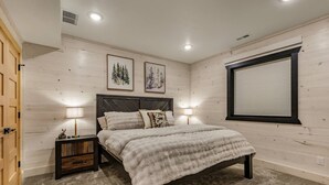 A bedroom with a bed, two bedside tables with lamps, a window with blinds, and two framed pictures on the wall. - Emerald Pines Lodge+HotTub+Cent AC+20mYellowstone (Island Park)