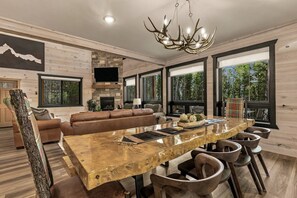 Una sala moderna con una gran mesa de comedor de madera, un sofá de cuero y una chimenea.