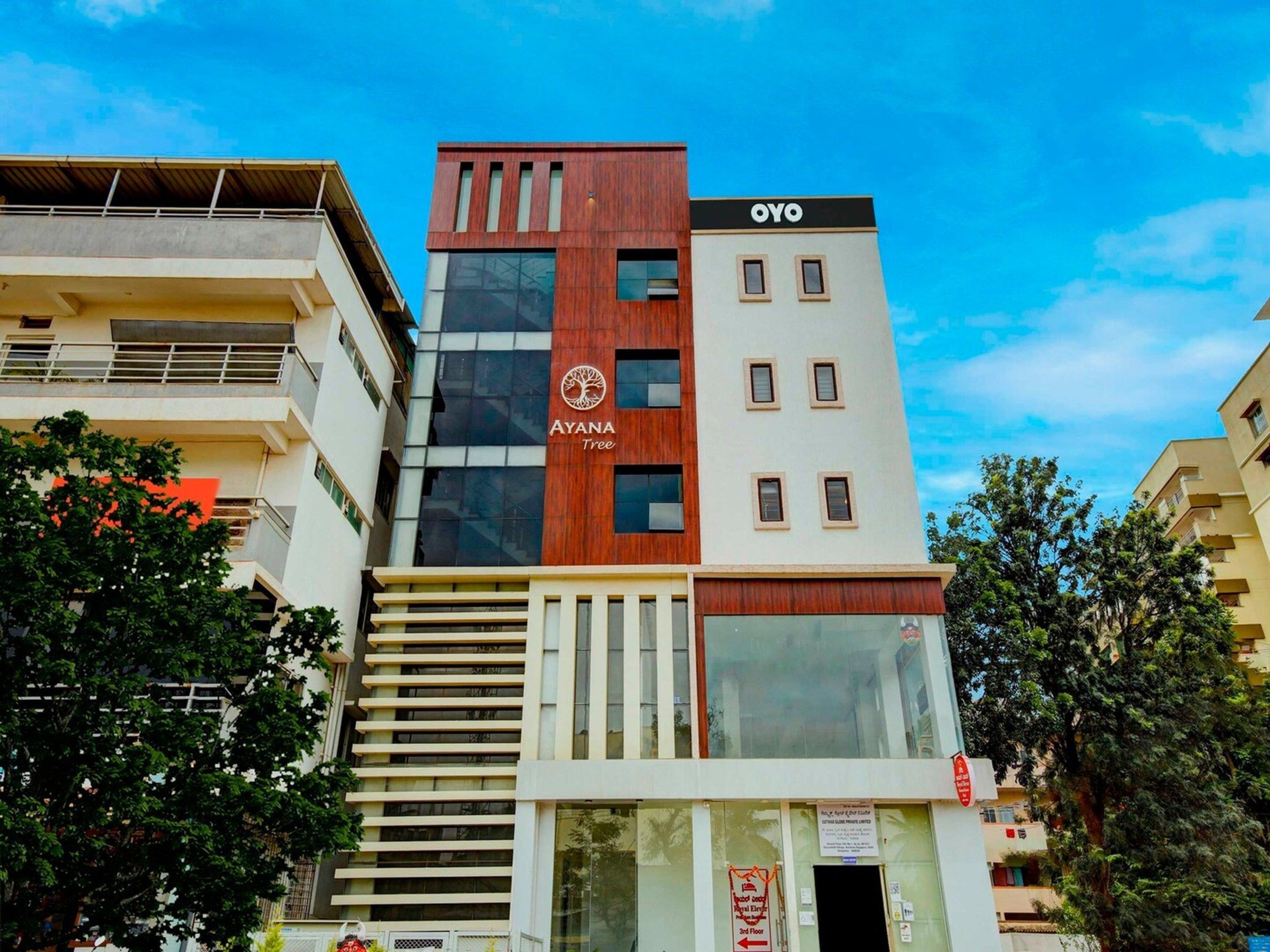 Ein mehrstöckiges Gebäude mit einem markanten 'AYANA Tree'-Logo und 'OYO'-Branding an der Fassade.