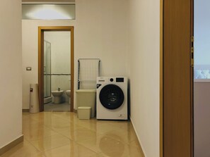 A laundry room with a washing machine, a drying rack, and a trash bin. - Family apartment in Shkoder: balcony, work corner, free parking (Shkodër)
