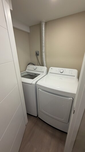 A laundry room with two white front-loading washing machines and a dryer.