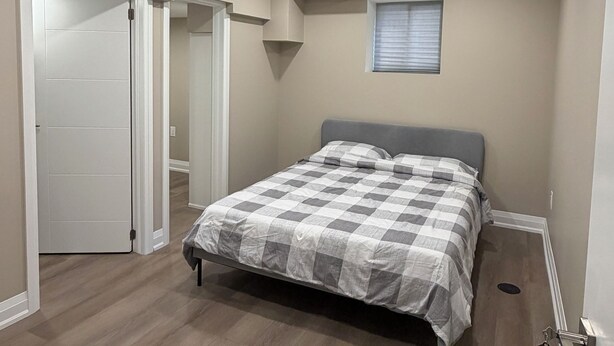 Ein Schlafzimmer mit einem Bett, einer Deckenleuchte, einem Fenster und einer Tür.