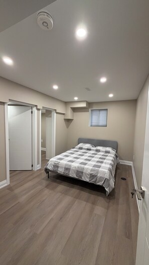 A bedroom with a bed, a ceiling light, a window, and a door.