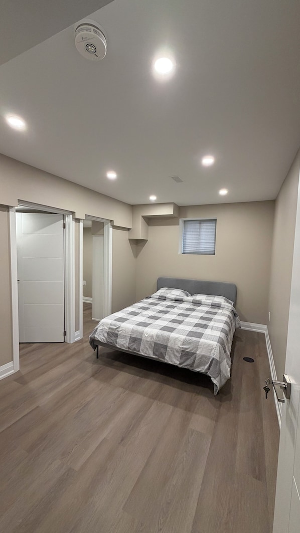 A bedroom with a bed, a ceiling light, a window, and a door. - Clean comfortable charming Beamsville stay (Lincoln)