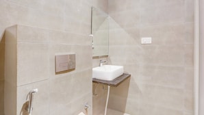 Un baño moderno con ducha, lavamanos y espejo.