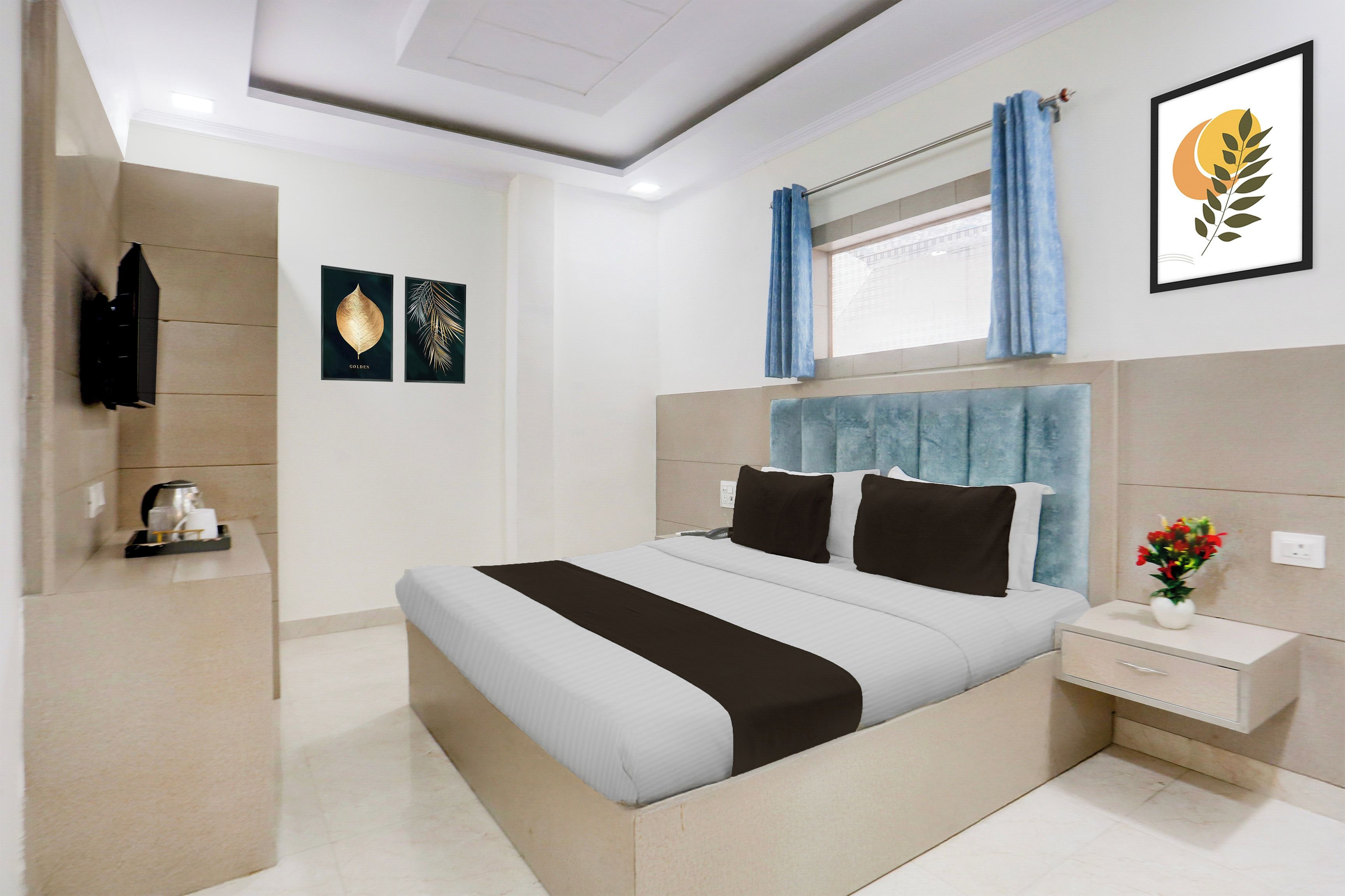 A modern hotel room with a large bed, a bedside table, a nightstand, a window with curtains, and artwork on the walls.
