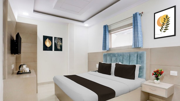 Una habitación de hotel moderna con una cama grande, una mesita de noche, cortinas en la ventana y obras de arte en las paredes.
