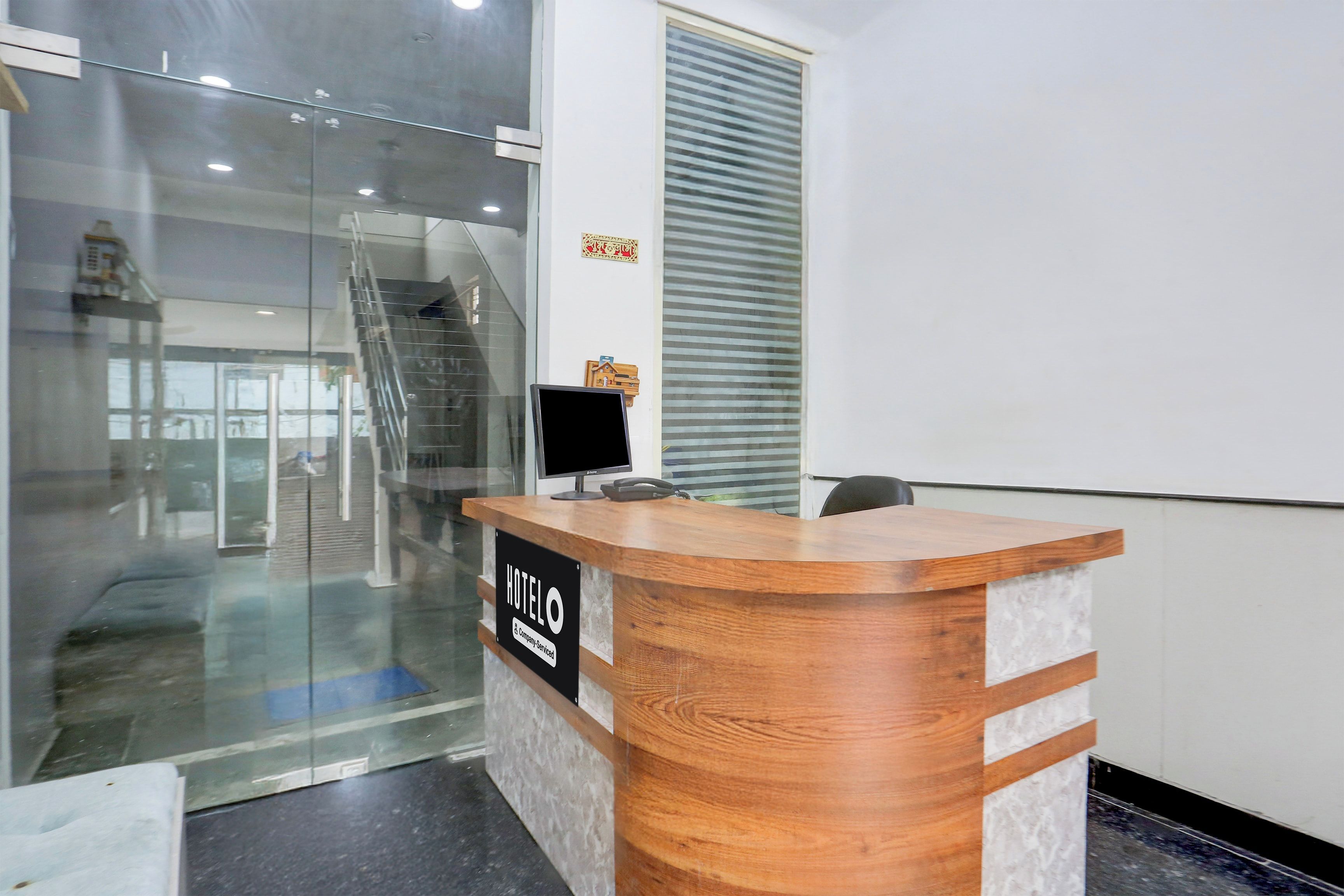 A hotel reception desk with a glass partition, a wooden counter, and a sign indicating 'HOTEL'.