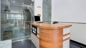 Una recepción de hotel con un separador de vidrio, una barra de madera y un letrero que dice 'HOTEL'.