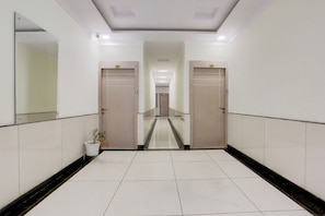 A corridor with two doors, a potted plant, and a tiled floor.