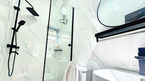 Et moderne badeværelse med bruseniche i glas, toilet og håndvask.
