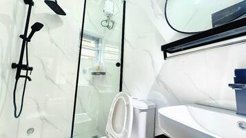 Un baño moderno con cabina de ducha de vidrio, inodoro y lavabo.