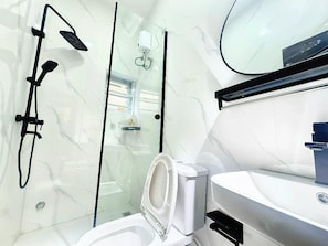 Een moderne badkamer met een douchecabine van glas, een toilet en een wastafel.