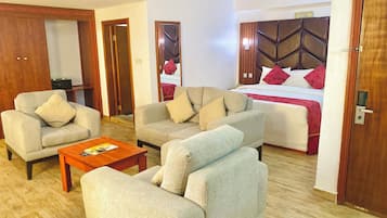 A hotel room with a bed, two sofas, a coffee table, and a wooden wardrobe.