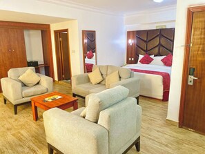 A hotel room with a bed, two sofas, a coffee table, and a wooden wardrobe. - Conitnental Exquisite Hotel by Reiz (Abuja)