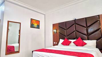 A hotel room with a large bed, a wooden headboard, a mirror, and a painting on the wall.