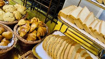 Variedad de panes y pasteles expuestos en bandejas y cestas.