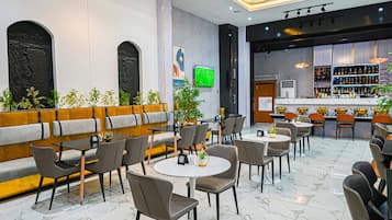 Un restaurant moderne doté d’un espace repas aménagé, d’un bar et d’un écran de télévision.