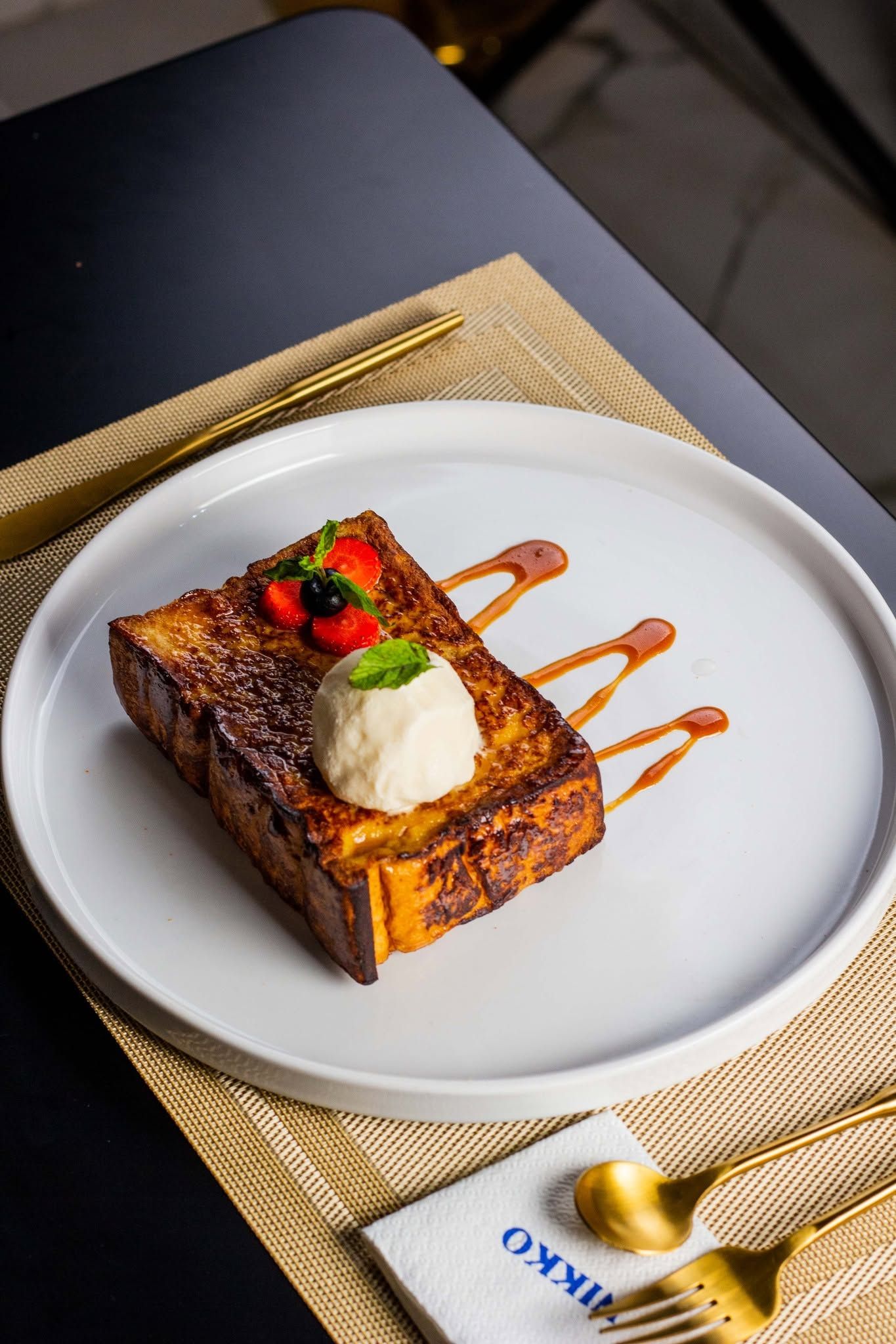 Een nagerechtbord met een sneetje toast, een bol ijs en een beetje saus.