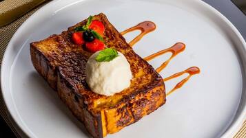 Een nagerechtbord met een sneetje toast, een bol ijs en een beetje saus.