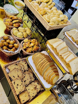 Un bufé con diversos panes, pasteles y una hogaza grande.
