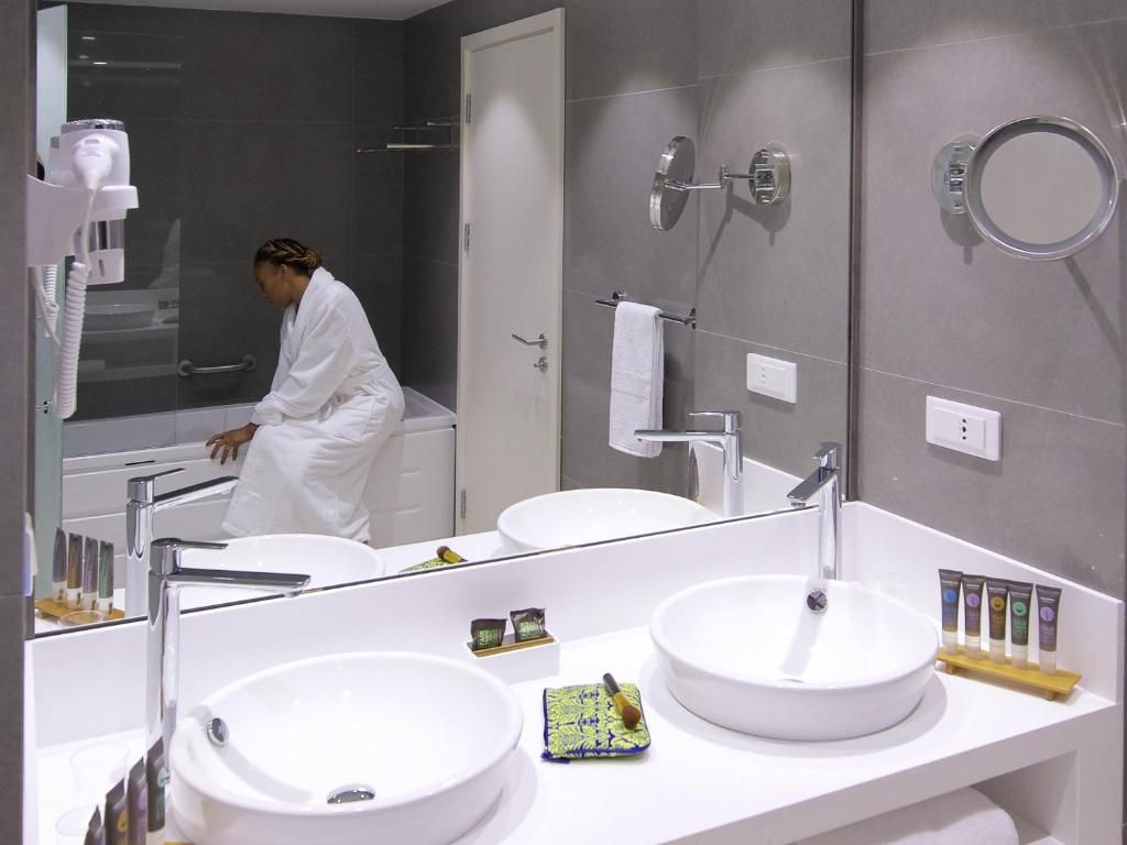 Casa de banho moderna com duas pias, um espelho grande e um secador de cabelo.