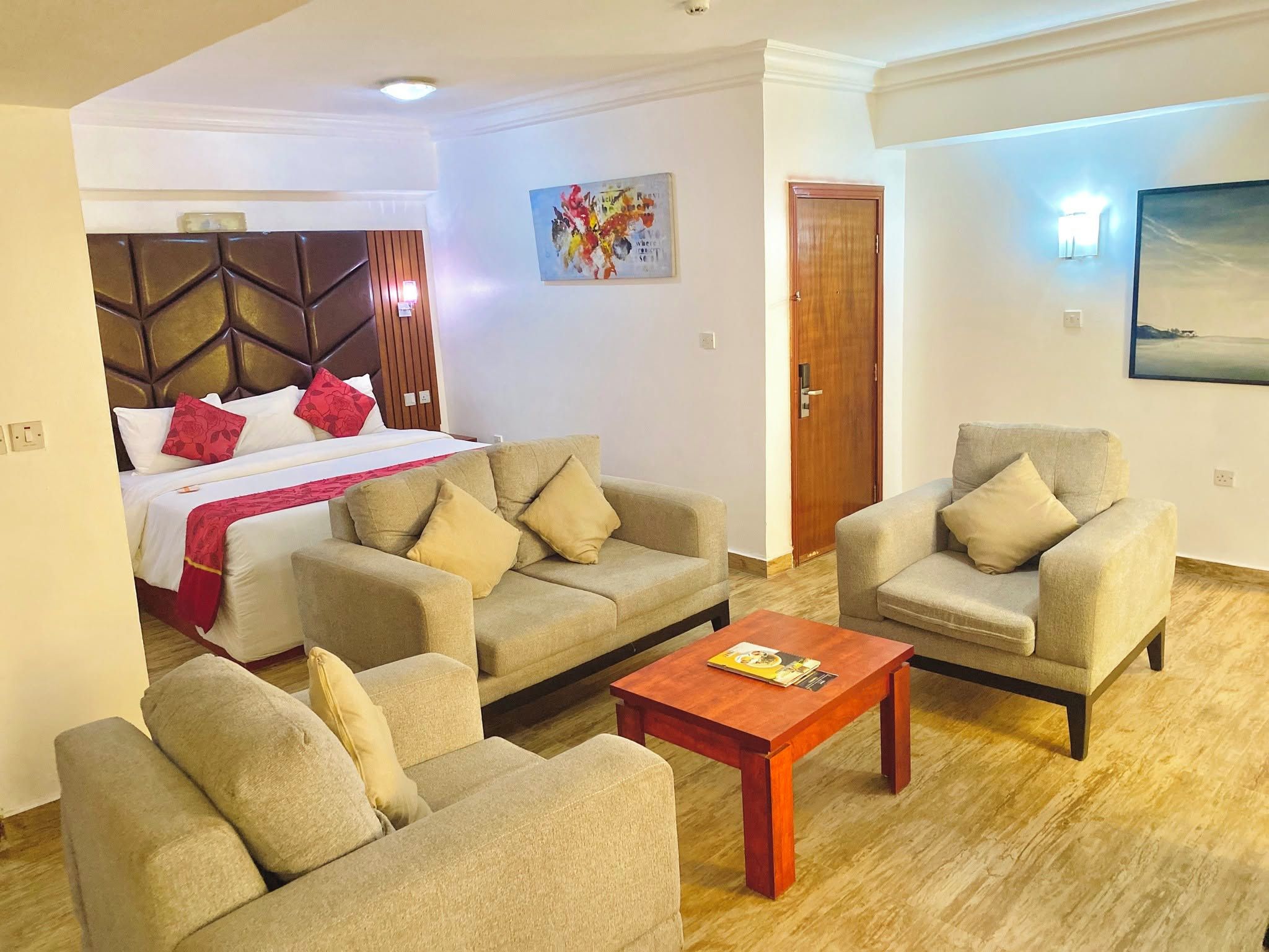 Habitación de hotel con cama, dos sofás, una mesa de centro y un cuadro en la pared.