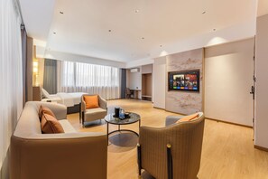 Habitación de hotel con sofá, sillón y una pequeña mesa con bandeja.