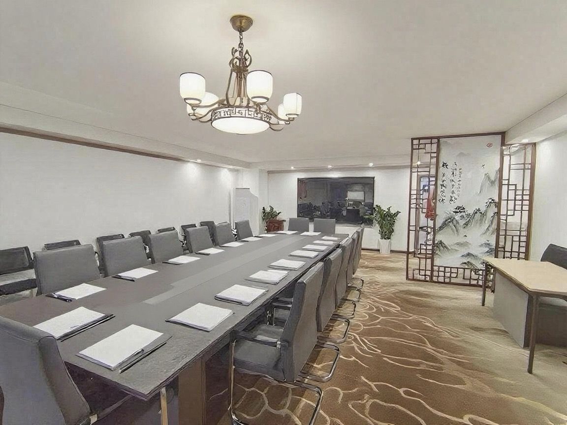 A conference room with a long table, chairs, a chandelier, and a decorative screen with calligraphy.