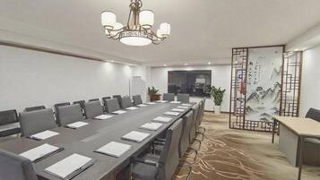 A conference room with a long table, chairs, a chandelier, and a decorative screen with calligraphy.