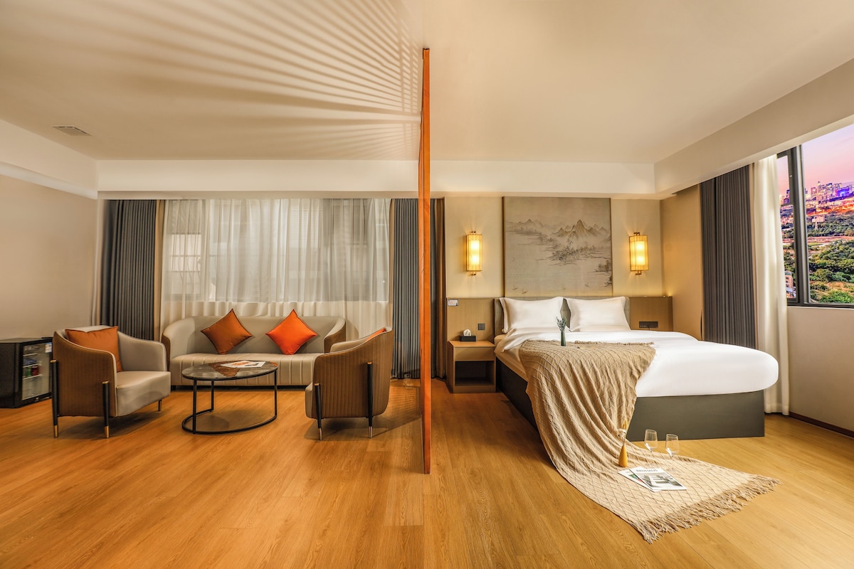 A hotel room with a bed, a sofa, a coffee table, and a nightstand.