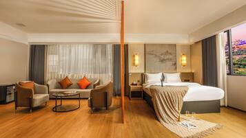 A hotel room with a bed, a sofa, a coffee table, and a nightstand.