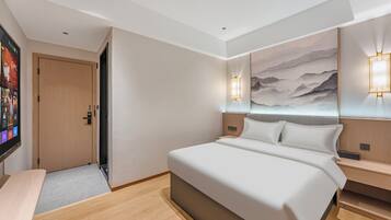 Ein modernes Hotelzimmer mit einem großen Bett, einem Flachbildfernseher und einem Gemälde an der Wand.