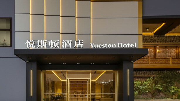 Yueston Hotel set med en moderne facade, oplyst indgang og traditionelle arkitektoniske detaljer.