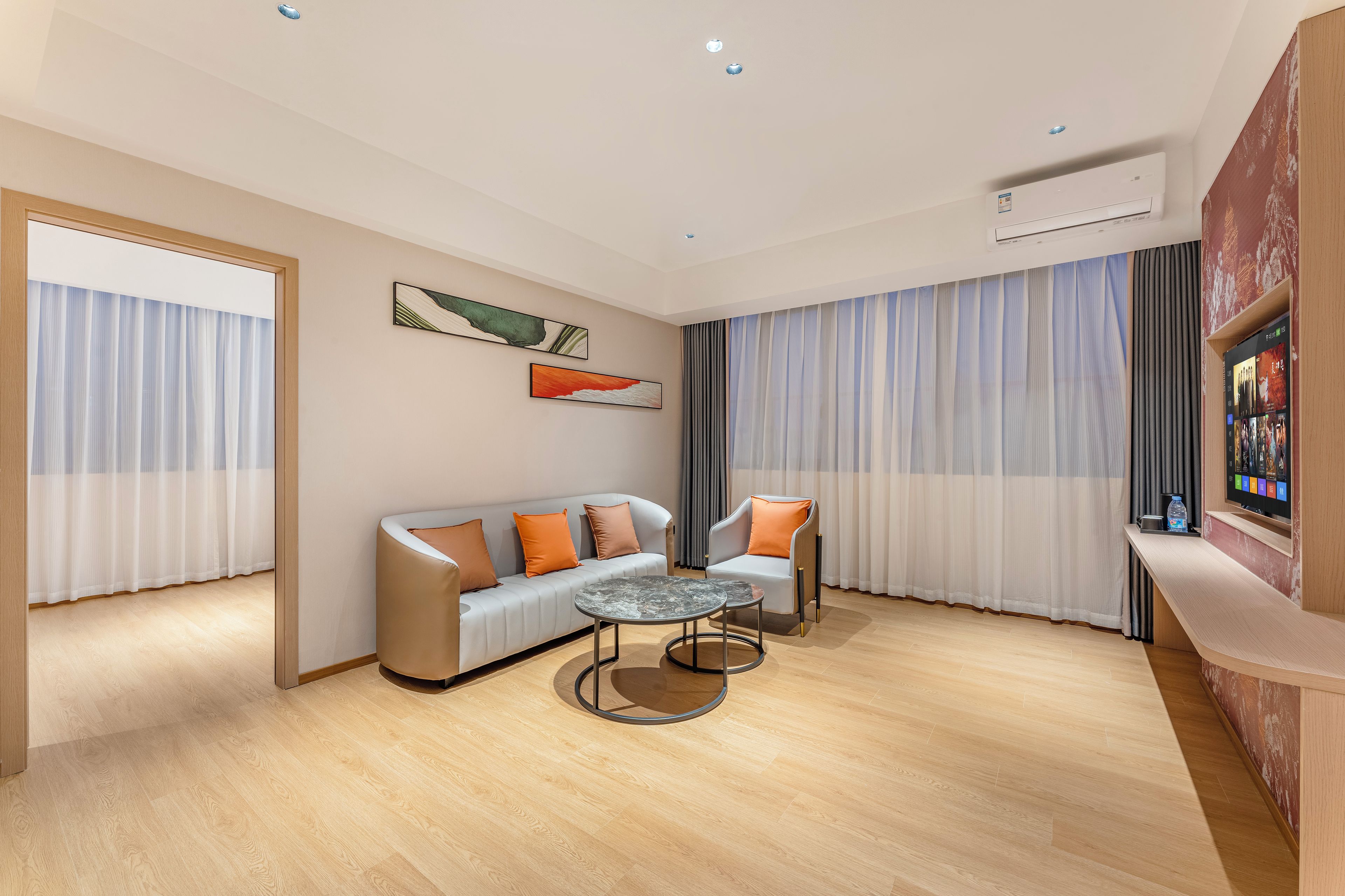 Una sala de estar moderna con un sofá, un sillón, una mesita de centro y un televisor de pantalla plana montado en una pared de madera.