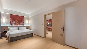 Un dormitorio moderno con cama, mesitas de noche, un televisor montado en la pared y una puerta de madera.