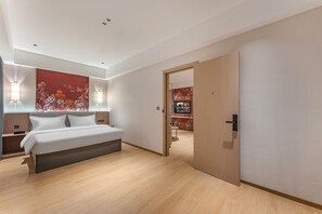 Un dormitorio moderno con cama, mesitas de noche, un televisor montado en la pared y una puerta de madera.