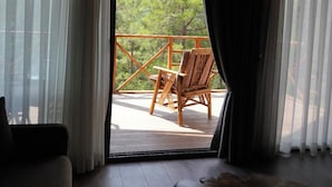 Una habitación con vistas a un paisaje montañoso, una silla de mimbre y una mesa.
