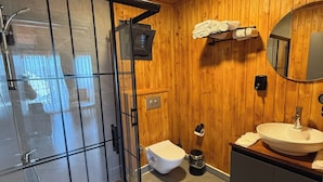 Un baño moderno con cabina de ducha de vidrio, inodoro, lavamanos y espejo.