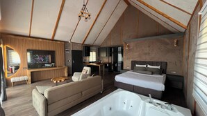 Un interior moderno con una cama grande, una zona de estar con sofá, una mesa de comedor y una bañera amplia.