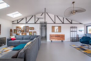 Una sala moderna con un sofá gris, un armario de madera y una silla azul.