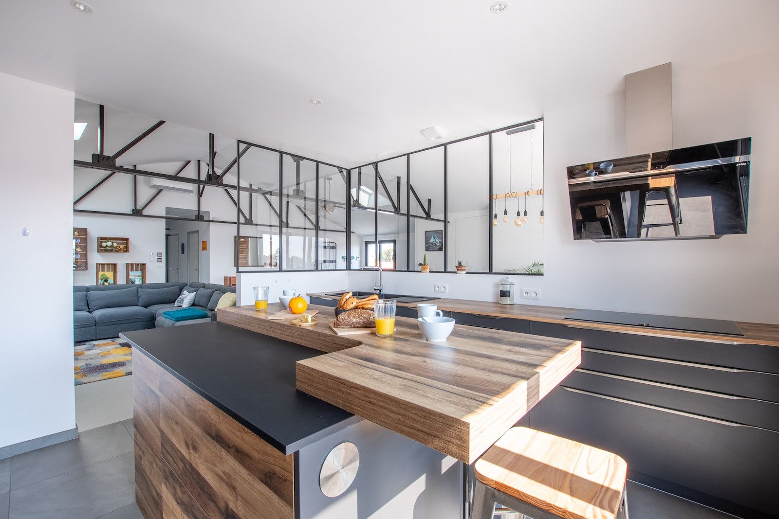 A modern kitchen with a central island, a dining area, and a living space with a sofa and coffee table.
