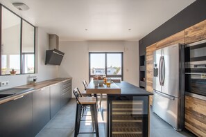 Una cocina moderna con una isla central, electrodomésticos de acero inoxidable y un amplio ventanal que proporciona luz natural.
